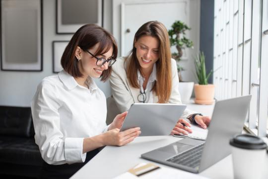 Two women reviewing a table in front of a laptop. 