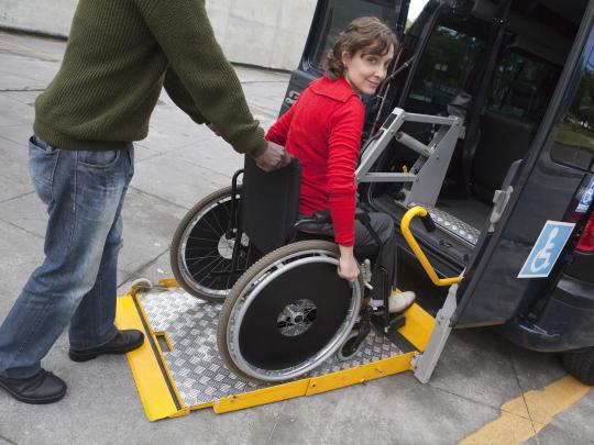 Woman in wheelchair being wheeled into van 